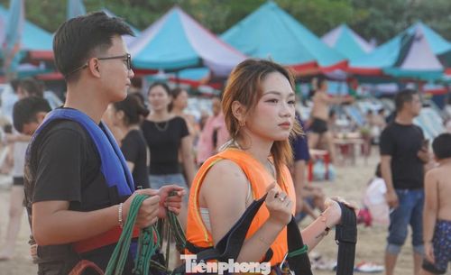 Trong khi đó, người lớn, thanh thiếu niên tranh thủ tắm cát, phơi nắng, chơi dù lượn, thuyền chuối giải trí dịp nghỉ lễ.