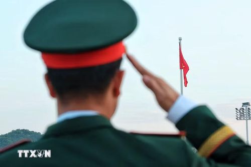 Một quân nhân thực hiện nghi lễ chào Quốc kỳ khi lá cờ đỏ sao vàng được kéo lên trên Quảng trường Ba Đình. (Ảnh: Phạm Tuấn Anh/TTXVN)