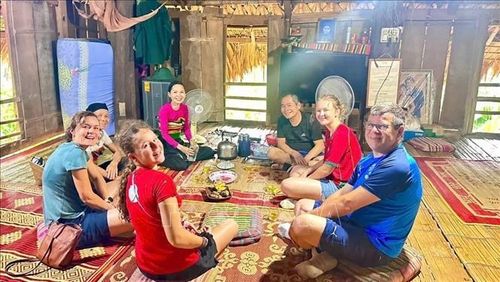 Du khách quốc tế trải nghiệm ẩm thực cùng người dân tộc Thái ở Pù Luông. Ảnh: TTXVN phát