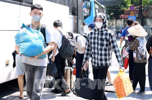 Người dân vất vả với đồ đạc bên cạnh tại bến xe Giáp Bát vội vã trở về nhà. Ảnh: Quốc Khánh - TTXVN