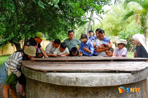 Du khách tham quan giếng nước đình làng Thạch Tân. Ảnh: HOÀNG ĐẠO