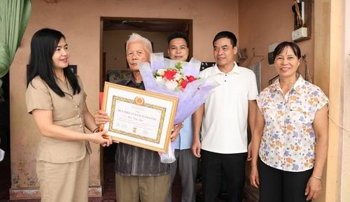 Phó Bí thư Thường trực Đảng ủy xã Tam Hưng Nguyễn Thị Bích Thuỷ thăm và trao tặng Huy hiệu Đảng đợt 2-9 cho đồng chí Cao Văn Lục, đảng viên 55 năm tuổi Đảng. Ảnh: Bình Minh 