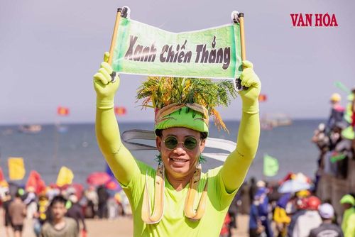 Một cổ động viên đội bó lúa chín, mặc trang phục xanh và giơ cao tấm bảng “Xanh chiến thắng”. Cách hóa trang vui nhộn, sáng tạo góp thêm sắc màu trẻ trung cho lễ hội truyền thống của làng biển