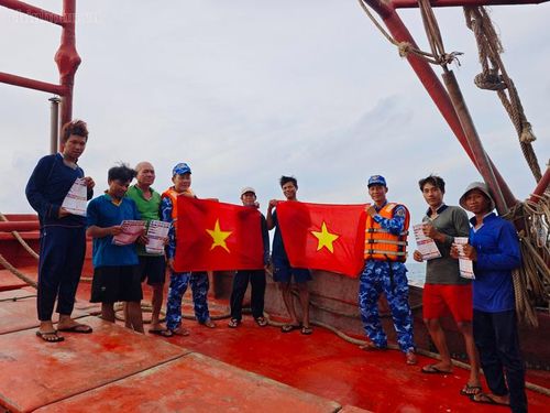 Cán bộ, chiến sĩ tàu CSB 4038 trao tặng cờ Tổ quốc cho bà con ngư dân - Ảnh: chinhphu.vn