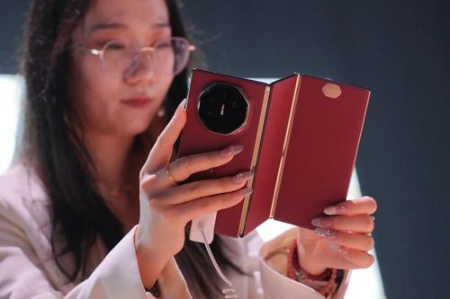Nhân viên Huawei cầm trên tay mẫu smartphone gập ba Mate XT trong sự kiện ra mắt sản phẩm năm 2025. Ảnh: EPA-EFE
