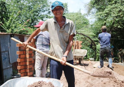 Ông Dũng xúc cát cùng mọi người xây nhà cho gia đình mình