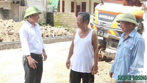 Ông Nguyễn Tùng Mậu (ở giữa) cùng người dân tháo dỡ công trình phụ, tường rào của gia đình để hiến đất mở rộng đường. Ảnh: Song Hoàng