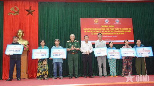 Trung tướng, Anh hùng LLVT nhân dân Nguyễn Đức Soát, nguyên Phó tổng Tham mưu trưởng, Chủ tịch Hội Hỗ trợ khắc phục hậu quả bom mìn Việt Nam và ông Huỳnh Văn Tịnh, Phó bí thư Thường trực Đảng ủy xã Sơn Tịnh trao hỗ trợ sinh kế cho nạn nhân bom mìn. Bà Phan Thị Nguyệt đứng ở ngoài cùng bên phải. Ảnh: NGỌC MINH
