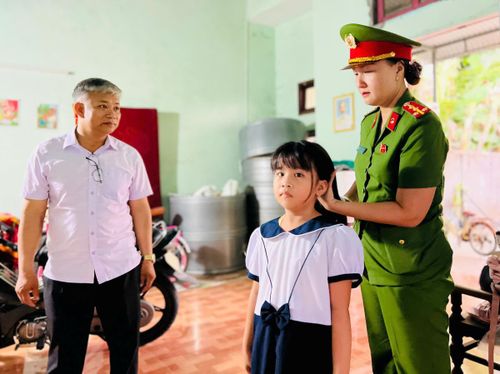Nữ chiến sĩ Công an xã Thu Bồn mặc bộ đồ đồng phục cho bé Khánh Ngân.