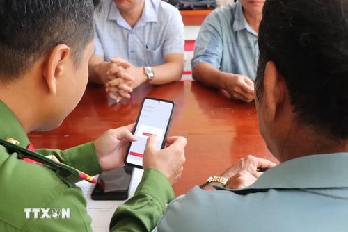 Thành viên Tổ công nghệ số cộng đồng "cầm tay chỉ việc" hướng dẫn người dân cách nộp hồ sơ trực tuyến. (Ảnh: Thu Hiền/TTXVN)