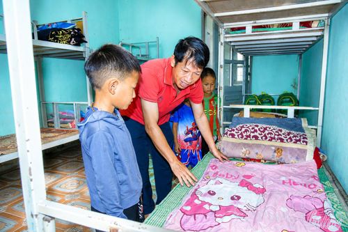 Thầy Đặng Thái Ân hướng dẫn học sinh bán trú sắp xếp, gấp gọn chăn gối, chuẩn bị nền nếp sinh hoạt.