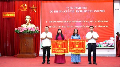 Bí thư Đảng ủy, Chủ tịch HĐND xã Bình Minh Nguyễn Khánh Bình và Phó Bí thư Thường trực Đảng ủy xã Lê Văn Ân trao Cờ thi đua của UBND thành phố cho 2 đơn vị tiêu biểu. Ảnh T. Đạt