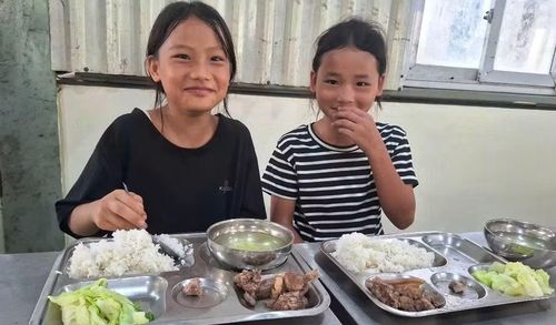 Giàng Thị Thánh (trái) và Tráng Thị Đông rất vui khi được ăn bữa cơm ở trường sau lễ khai giảng.