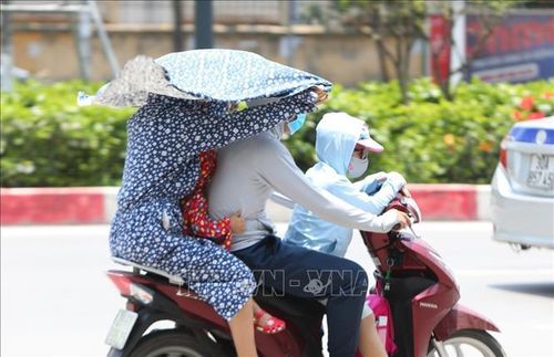 Người dân ở TP Hồ Chí Minh tìm mọi cách tránh nắng khi tham gia giao thông. Ảnh: Thành Đạt/TTXVN