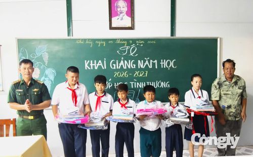 Trung tá Trần Bình Phục, Phó đội trưởng Vận động Quần chúng (Đồn biên phòng Hòn Chuối) và người dân tặng quà cho các em học sinh “Lớp học tình thương” tại Lễ khai giảng năm học mới trên đảo.