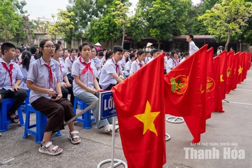 Sân trường ngập sắc trắng của đồng phục học sinh, sắc đỏ của khăn quàng và màu xanh của hàng cây.