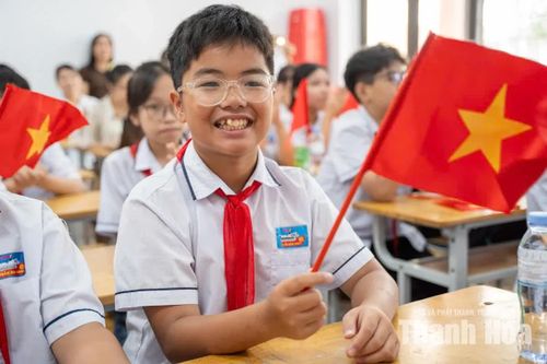 Học sinh hào hứng cầm cờ Tổ quốc trong lớp học, chờ đón khoảnh khắc tiếng trống khai giảng năm học mới vang lên.