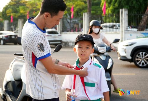 Phụ huynh sửa soạn áo quần tươm tất cho con. Ảnh: HỒ QUÂN