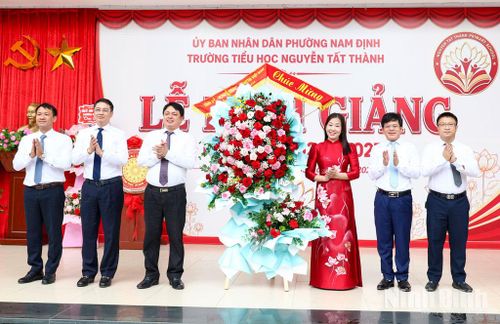 Các đồng chí: Trần Minh Thắng, Ủy viên Ban Thường vụ Tỉnh ủy, Bí thư Đảng ủy, Chủ tịch HĐND phường Nam Định; Phạm Quang Ái, Tỉnh ủy viên, Giám đốc Sở Ngoại vụ tặng Trường Tiểu học Nguyễn Tất Thành lẵng hoa thắm. Ảnh: Xuân Thu