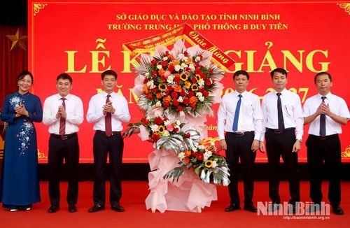 Các đồng chí: Nguyễn Đức Toàn, Ủy viên Ban Thường vụ Tỉnh ủy, Trưởng Ban Tuyên giáo Tỉnh ủy; Phạm Anh Tuấn, Tỉnh ủy viên, Trưởng Ban Văn hóa - Xã hội, Hội đồng nhân dân tỉnh tặng hoa chúc mừng Trường THPT B Duy Tiên. Ảnh: Phùng Thống