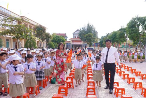 Nhà giáo Mạc Hoàng Huyên - Hiệu trưởng Trường Tiểu học Cổ Lễ ân cần dắt tay các em học sinh lớp 1 bước vào sân trường trong ngày khai giảng