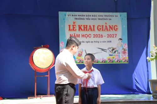 Anh Lê Xuân Hạnh, giáo viên Trường Tiểu học Trường Sa trao khăn quàng đỏ cho học sinh Vi Quý Đăng.