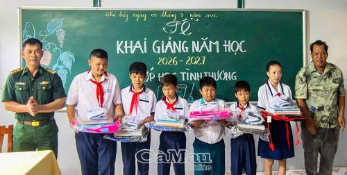  Trung tá Trần Bình Phục, giáo viên phụ trách lớp, cùng ông Kim Ngọc Hậu, phụ huynh, tặng quà động viên học sinh Lớp học tình thương trên đảo. (Ảnh: Đồn Biên phòng Hòn Chuối cung cấp)