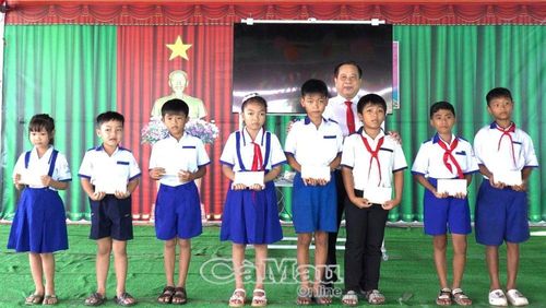 Ông Huỳnh Minh Nguyên, Bí thư Đảng uỷ, Chủ tịch HĐND xã Khánh Lâm, trao tập và học bổng cho học sinh Trường Tiểu học và THCS Trịnh Minh Hưởng nhân dịp khai giảng.