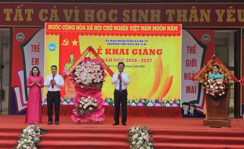 Trung tướng Đào Văn Nhận, Ủy viên Ban Thường vụ Thành ủy, Tư lệnh Bộ Tư lệnh Thủ đô Hà Nội trao tặng lẵng hoa chúc mừng thầy trò Trường Tiểu học Ba Vì B nhân ngày khai trường. Ảnh: PV