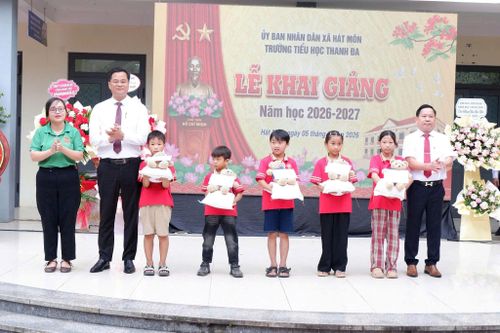 Phó Bí thư Thường trực Đảng ủy xã Hát Môn Dương Chí Thanh tặng quà cho các em học sinh Trường Tiểu học Thanh Đa nhân ngày khai trường. Ảnh: HM