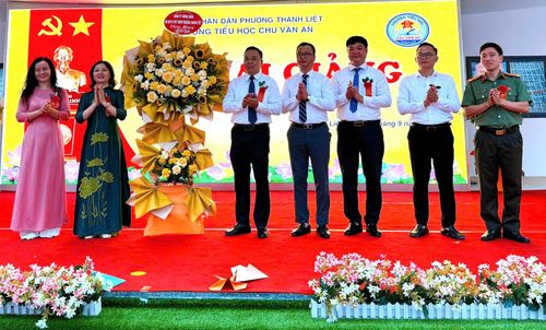 Lãnh đạo phường Thanh Liệt tặng hoa chúc mừng thầy cô và học sinh Trường Tiểu học Chu Văn An. Ảnh: PV