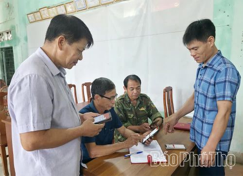 Đảng viên chi bộ thôn Bôi Cả hướng dẫn bà con thực hiện dịch vụ công và an sinh xã hội trực tuyến qua điện thoại thông minh.