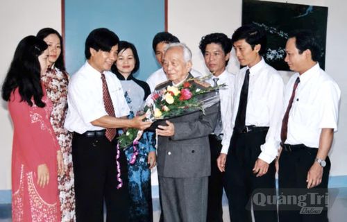 Nhà báo Tạ Đình Nam, Tổng Biên tập Báo Quảng Bình, thay mặt những người làm báo tỉnh nhà tặng hoa chúc mừng Đại tướng Võ Nguyên Giáp nhân chuyến Đại tướng về thăm quê hương (tháng 8/2002) - Ảnh: Tư liệu