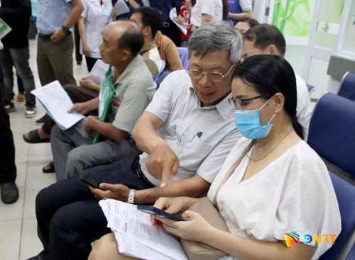 Phó Chủ tịch UBND thành phố Hồ Quang Bửu chia sẻ trải nghiệm app OneCare với một người dân đến khám bệnh. Ảnh: TRỌNG HUY