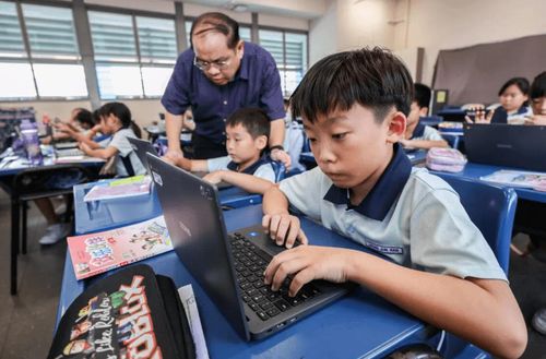 Trong khi học sinh tự thực hiện các nhiệm vụ, thầy Ng đi quanh lớp, quan sát và hỗ trợ những em cần giúp đỡ. Ảnh: Gavin Foo/The Straits Times