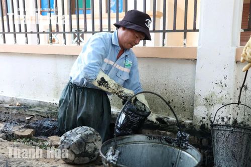 Công nhân dùng dụng cụ để gom bùn, rác dưới lòng cống.