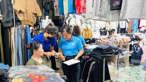 Các thành viên tổ công nghệ số cộng đồng và lực lượng đoàn viên, thanh niên trực tiếp hướng dẫn các hộ kinh doanh tiếp cận, cài đặt và sử dụng những tiện ích số tại chợ Cát Tiên