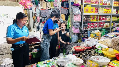 Các thành viên tổ công nghệ số cộng đồng và lực lượng đoàn viên, thanh niên trực tiếp hướng dẫn các hộ kinh doanh tiếp cận, cài đặt và sử dụng những tiện ích số tại chợ Cát Tiên