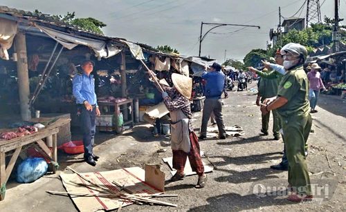 Lực lượng chức năng phường Quảng Trị hỗ trợ người dân di dời bạt che, bàn ghế lấn chiếm vỉa hè - Ảnh: K.S
