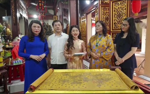 Hiệu trưởng Trường THCS Trần Duy Hưng (ngoài cùng bên trái) cùng lãnh đạo phường Yên Hòa tìm hiểu một trong những đạo sắc phong được lưu giữ tại cụm di tích Đình Trong - Đình Ngoài - Đền Dục Anh. Ảnh: PV