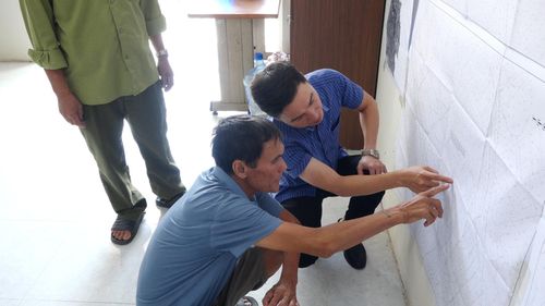 Ông Nguyễn Văn Hải tìm hiểu vị trí nhà, đất của gia đình trên bản đồ quy hoạch và trao đổi những vấn đề còn băn khoăn. Ảnh: Đỗ Duẩn