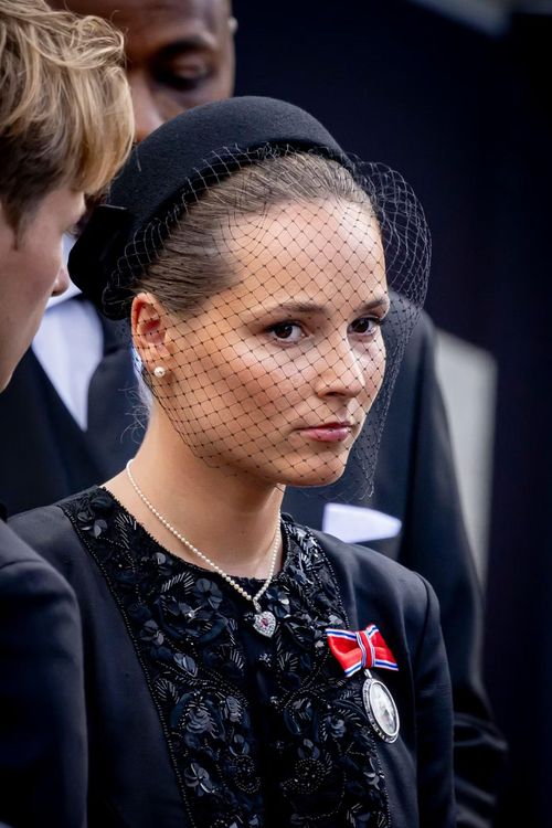 Thái nữ Ingrid Alexandra mặc áo khoác dài đen bên ngoài váy cùng màu, kết hợp mũ có mạng che mặt, trang sức ngọc trai và huy hiệu hoàng gia. Trước tang lễ ông nội, cô đã tuyên thệ trung thành với Hiến pháp Na Uy, chính thức trở thành người kế vị ngai vàng. Ảnh: Patrick van Katwijk.
