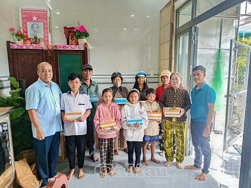 Ông Phạm Tiến Nguyên (bìa trái), Trưởng ban đại diện cha mẹ học sinh Trường THPT Võ Văn Kiệt, trao tập hỗ trợ học sinh có hoàn cảnh khó khăn trước thềm năm học mới.