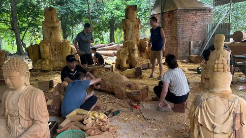 Những người thợ trong xưởng điêu khắc của Nghệ nhân Nguyễn Văn Trúc đang miệt mài trao đổi công việc. Ảnh: PV