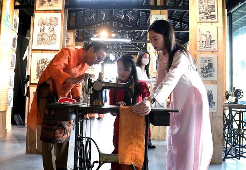 Nghệ nhân hướng dẫn các bạn trẻ cách sử dụng máy may cổ.