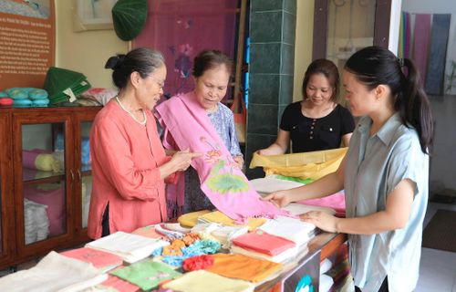 Nghệ nhân ưu tú Phan Thị Thuận (xã Hồng Sơn) giới thiệu sản phẩm khăn lụa tơ sen. Ảnh: Quang Thái