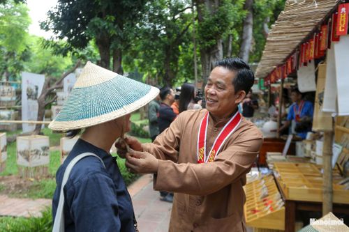 Nghệ nhân làng nghề đan cói Kim Sơn (Ninh Bình) tỉ mỉ trình diễn kỹ thuật tạo hình sản phẩm thủ công, thu hút sự chú ý của đông đảo công chúng trẻ tuổi.