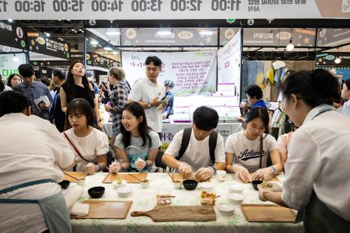 Khách tham quan tự tay làm món cuốn chay tại một gian hàng chuyên về ẩm thực chùa chiền trong hội chợ. Ảnh: New York Times.