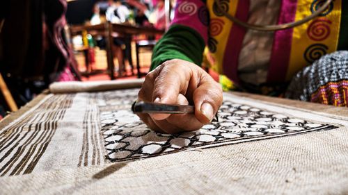 Đôi bàn tay khéo léo của người phụ nữ Mông tỉ mỉ vẽ sáp ong, tạo nên những đường hoa văn truyền thống trên nền vải lanh.