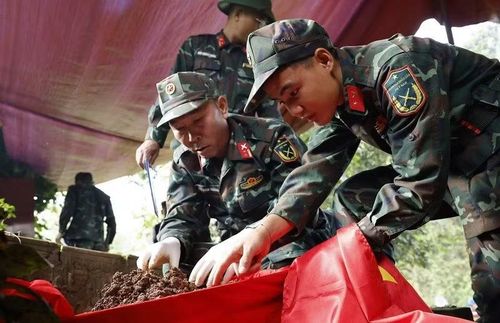 Trung tá Đào Xuân Trường (bên trái ảnh) đang cẩn thận cất bốc hài cốt liệt sĩ. (Ảnh: LÊ LAN)